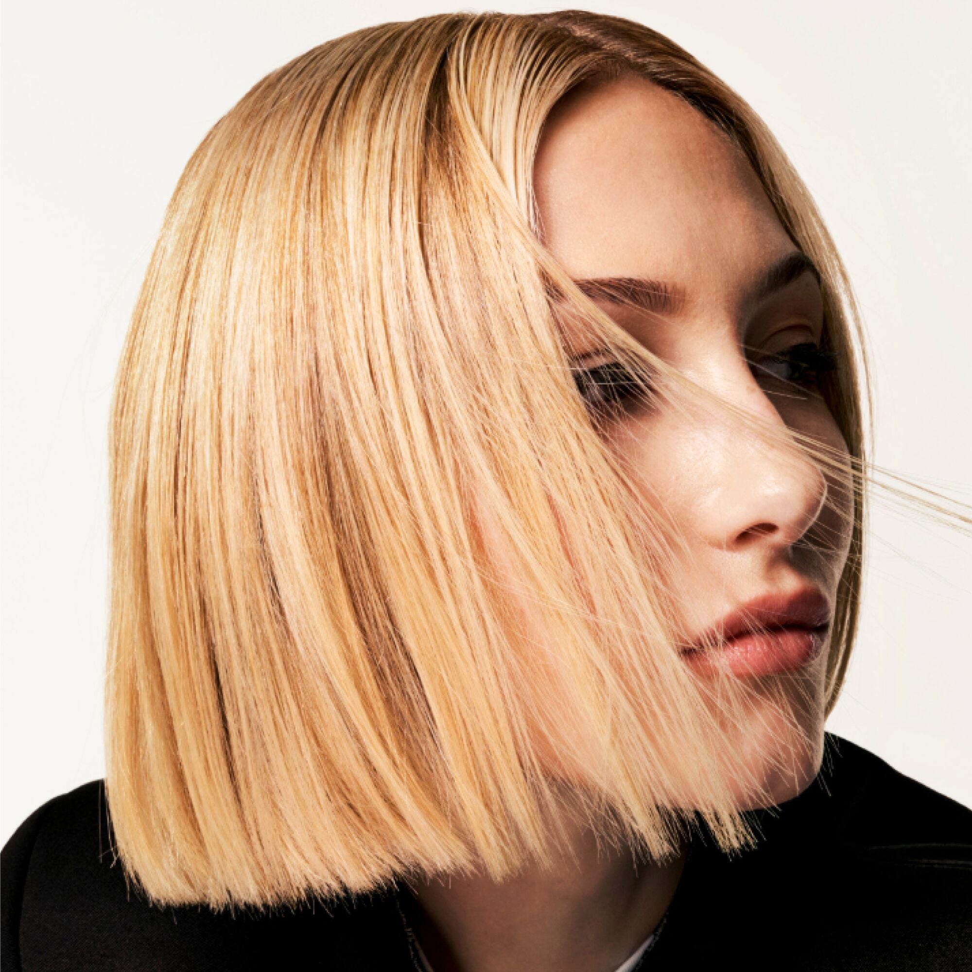 Mujer con un elegante corte de pelo rubio sobre un fondo neutro