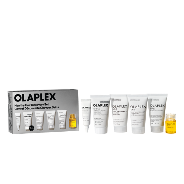 A retail packshot of the Olaplex Healthy Hair Discovery Set against a transparent checkerboard background. On the left is the product box, and arranged to the right are five white travel-size tubes (No. 3, No. 4, No. 5, No. 6, and a smaller tube) alongside a small clear bottle of No. 7 Bonding Oil filled with yellow liquid. - main view