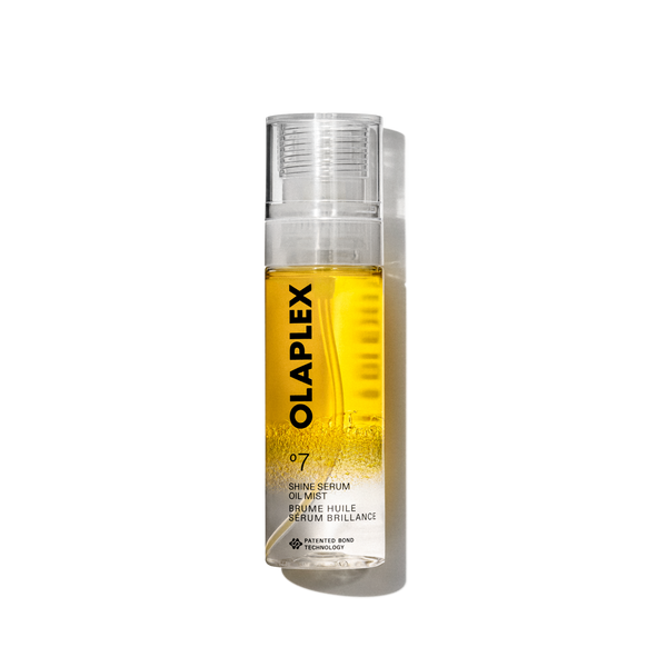 Imagen de producto del Olaplex No. 7 Shine Serum Oil Mist en un pulverizador transparente de 80 ml. La botella contiene un líquido amarillo brillante visible en su interior, una tapa transparente y una etiqueta blanca limpia en la parte inferior con texto negro que muestra el nombre del producto, los detalles y la firma “No.” Logotipo de 7". La botella aparece aislada sobre un fondo de cuadrícula transparente. - main view