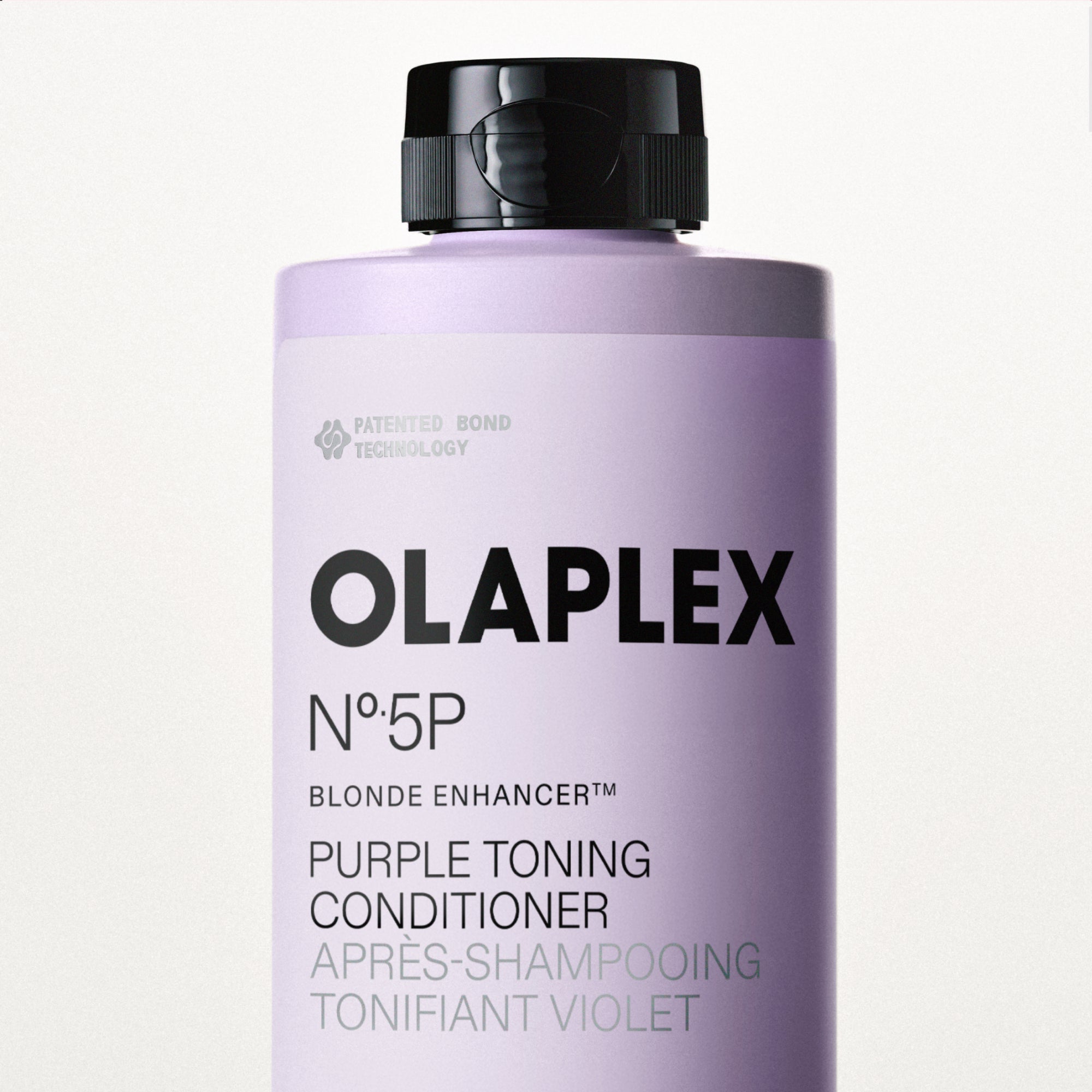 A close-up shot focusing on the top half of an Olaplex No. 5P Blonde Enhancer Purple Toning Conditioner bottle, highlighting its sleek black cap and light purple label against a clean white background.