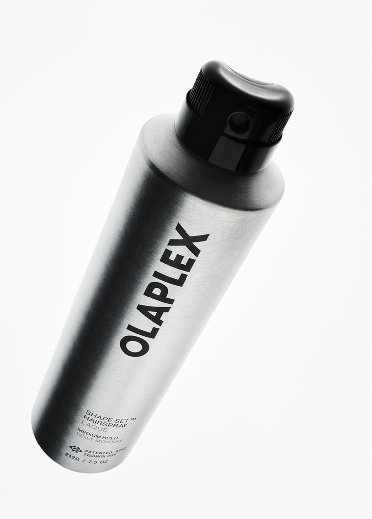 Olaplex Shape-Set Hair Spray in a sleek, metallic silver aerosol can with a black nozzle cap, shown at an angle on a clean white background.